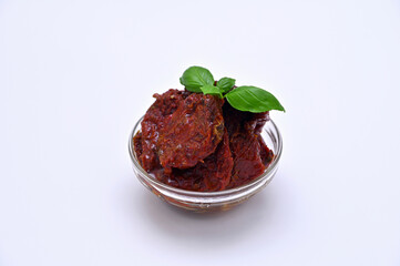 sun-dried tomatoes in oil in a glass bowl on a white background