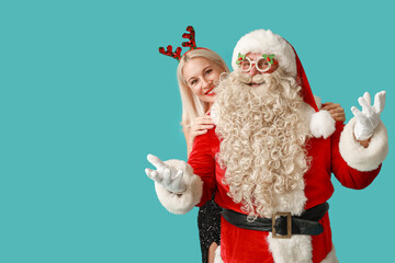 Santa Claus with beautiful mature woman in Christmas deer horns and glasses on blue background