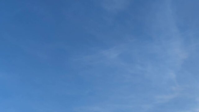 Clouds are floating across the sky. Blue sky with white cirrus clouds that are slowly moving across the sky. They are located at different heights and change their shape and size as they go. It's gett