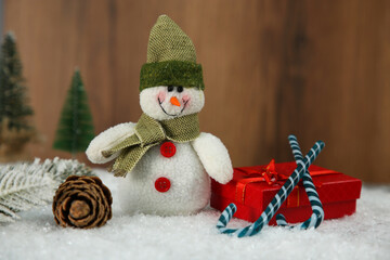 Cute decorative snowman and other Christmas decor on artificial snow