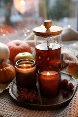 Burning candles, freshly brewed tea and autumn decor on fabric