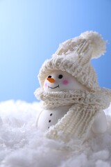 Cute decorative snowman on artificial snow against light blue background