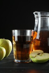 Tasty fresh apple juice and fruits on black wooden table
