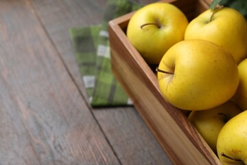 Ripe yellow apples in crate on wooden table, closeup. Space for text