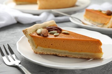 Piece of tasty homemade pumpkin pie with seeds and nuts on grey table, closeup