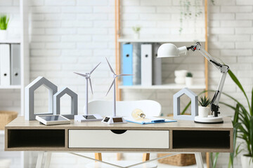 Wind turbine models with light bulb and solar panel on table in office. Green Energy concept