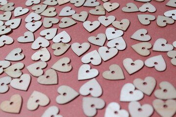 Collection of small wooden hearts against a dark pink background