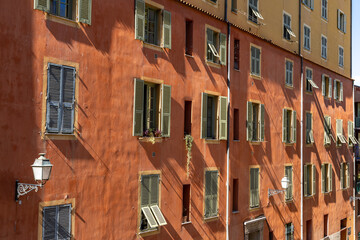 a house with a red facade and windows with shutters