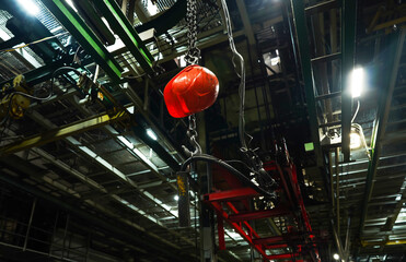 Incident with a worker at a factory. Incident on a production line. Helmet on a crane hook in a factory workshop. Red safety helmet in Assembly line on industrial plant. Soft focus, sharpening.