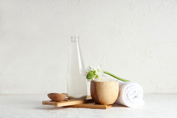 Bottle of natural rice water, grains, flower and clean towel on light background
