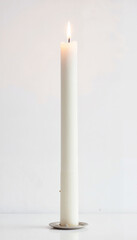 Elegant White Candle with Gentle Flame against Neutral Background with Copy Space