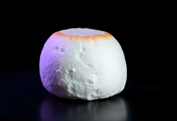 Fototapeta premium a large, perfectly round marshmallow, with a slightly toasted edge, isolated on a deep black background, creating a strong contrast create with ai