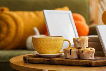 Cup of tea with muffins on table in living room, closeup