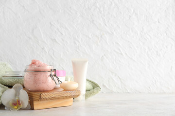 Spa composition with natural body scrub and burning candle on light background