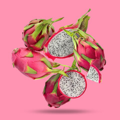 Yummy pitaya fruits falling on pink background