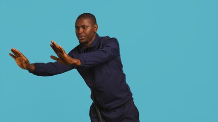 Portrait of security guard pushing back intruders while overseeing premises. Private law...