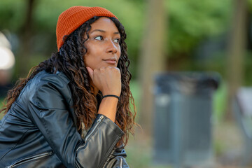 young woman sitting thoughtfully outdoors in autumn