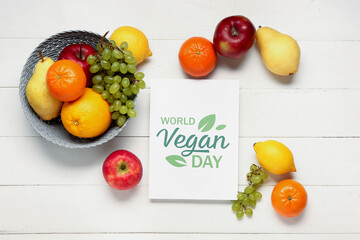 Card with text WORLD VEGAN DAY and basket of fresh fruits on white wooden background