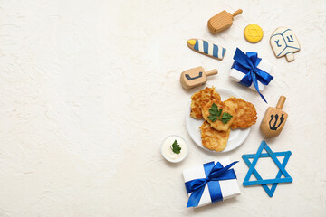 Composition for Hanukkah celebration with potato pancakes, gift boxes and dreidels on white grunge background