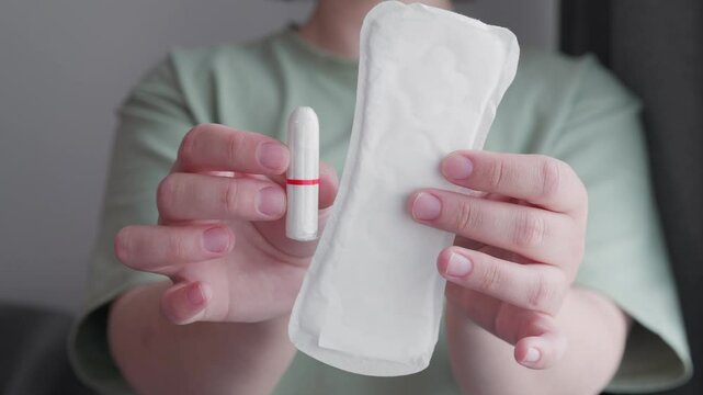 woman holding hygiene pad and tampon making decision of hygienic products choosing menstrual cup. choose alternative eco friendly variant of protection during menstruation.