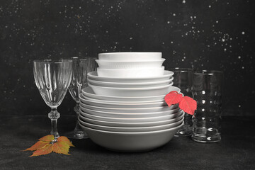 Stack of dishes with autumn leaves on table against black background