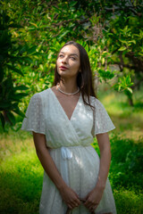 Fototapeta premium A woman peacefully walking between vibrant lemon trees, enjoying the fresh, natural surroundings, creating a calm and serene atmosphere in a garden.