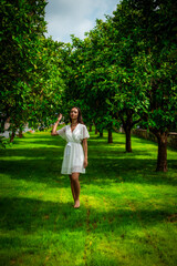 A woman peacefully walking between vibrant lemon trees, enjoying the fresh, natural surroundings, creating a calm and serene atmosphere in a garden.