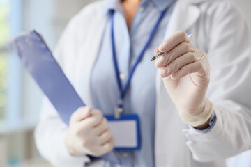 Female chemist with pen and clipboard in laboratory, closeup