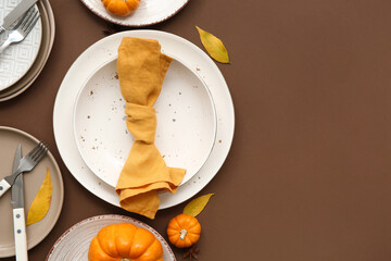 Beautiful table setting with fresh pumpkins, star anise and autumn leaves on brown background