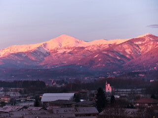profile of a Piedmont alp overlooks the Po Valley immersed in a pink sunset