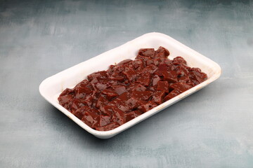 Cut raw beef liver with onions, spices, chili peppers and dill on wooden table, flat lay