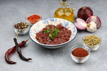 Cut raw beef liver with onions, spices, chili peppers and dill on wooden table, flat lay