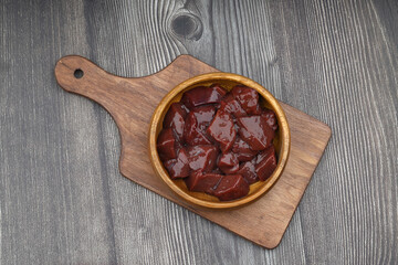 Cut raw beef liver with onions, spices, chili peppers and dill on wooden table, flat lay