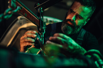 Focused mechanic using tools to repair a vehicle engine