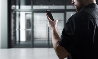 Business person hands using smartphone at office building.