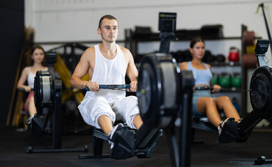 Fototapeta premium Strong sportsman training at cable row machine in modern crossfit gym