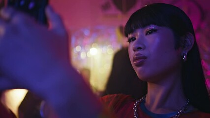 Girl making selfie nightclub at glittery event closeup. Beautiful Asian woman
