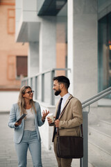 Business people having informal meeting while walking outside of office building