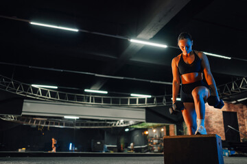 Determined sportswoman lifting weights on wooden box in gym
