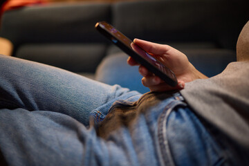 Enjoying a relaxing moment while seated on the couch, wearing jeans and using my phone