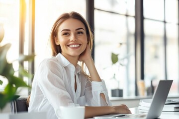 Obraz premium Happy woman in a white shirt sitting at her desk, smiling and looking away in a bright office.