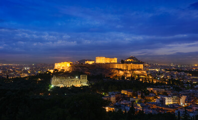 Obraz premium Famous greek tourist landmark - the iconic Parthenon Temple at the Acropolis of Athens as seen from Philopappos Hill in the evening blue hour, Athens, Greece