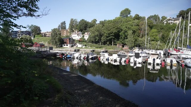 View of boats and houses reflecting in the water at Langviksbukta on a sunny day, Bygdoy, Oslo, Norway, Scandinavia, Europe
