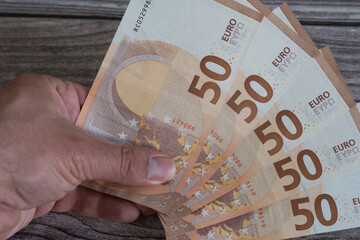 left hand of Caucasian man holding 50 euro bills