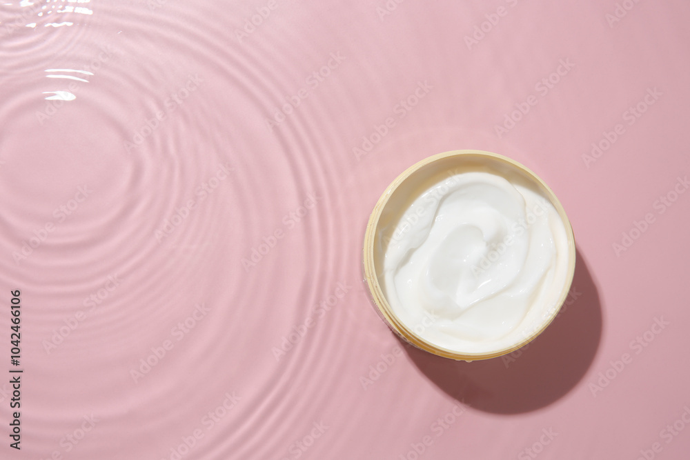 Sticker Cosmetic product. Jar with cream in water on pink background, top view. Space for text