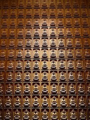 Intricate Wall of Buddha Carvings in a Grid Pattern Showcasing Spiritual Craftsmanship
