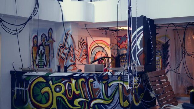 Empty industrial building with rubble and graffiti paint, concept of alternative lifestyle. Criminal hideout used by edgy teenagers to hangout and commit illegal drawing on walls, jib down and up shot