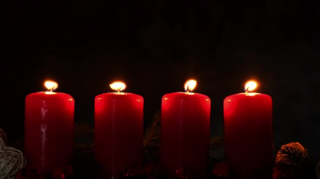 New year and Christmas preparation. Four red advent candles burning in dark room. Handmade eco-friendly decor. Sustainable Christmas decoration atmosphere