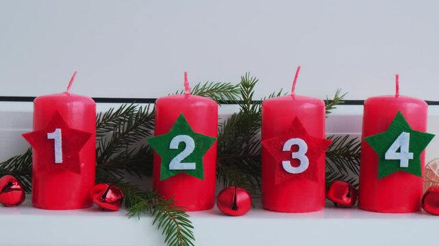New year and Christmas preparation. Four red advent candles with numbers in white windowsill. Handmade eco-friendly decor. Sustainable Christmas decoration hygge style