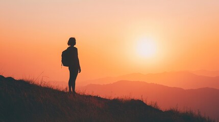 A lone hiker stands on a mountaintop, silhouetted against the setting sun, with rolling hills in the distance.